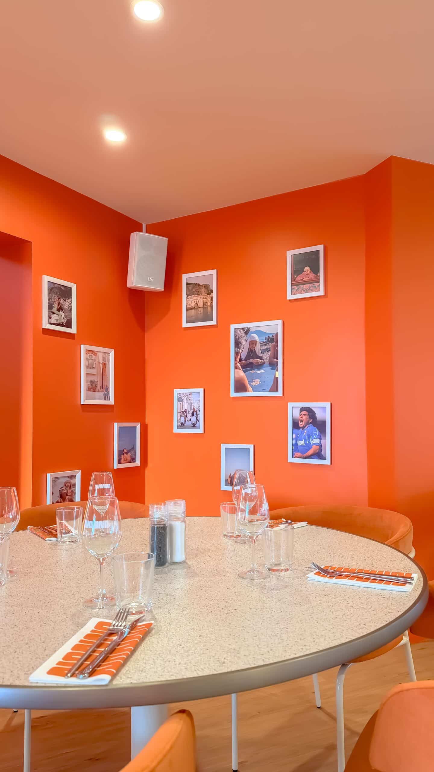 Table dressée dans un restaurant aux murs orange vif ornés de photos encadrées, dont Diego Maradona.